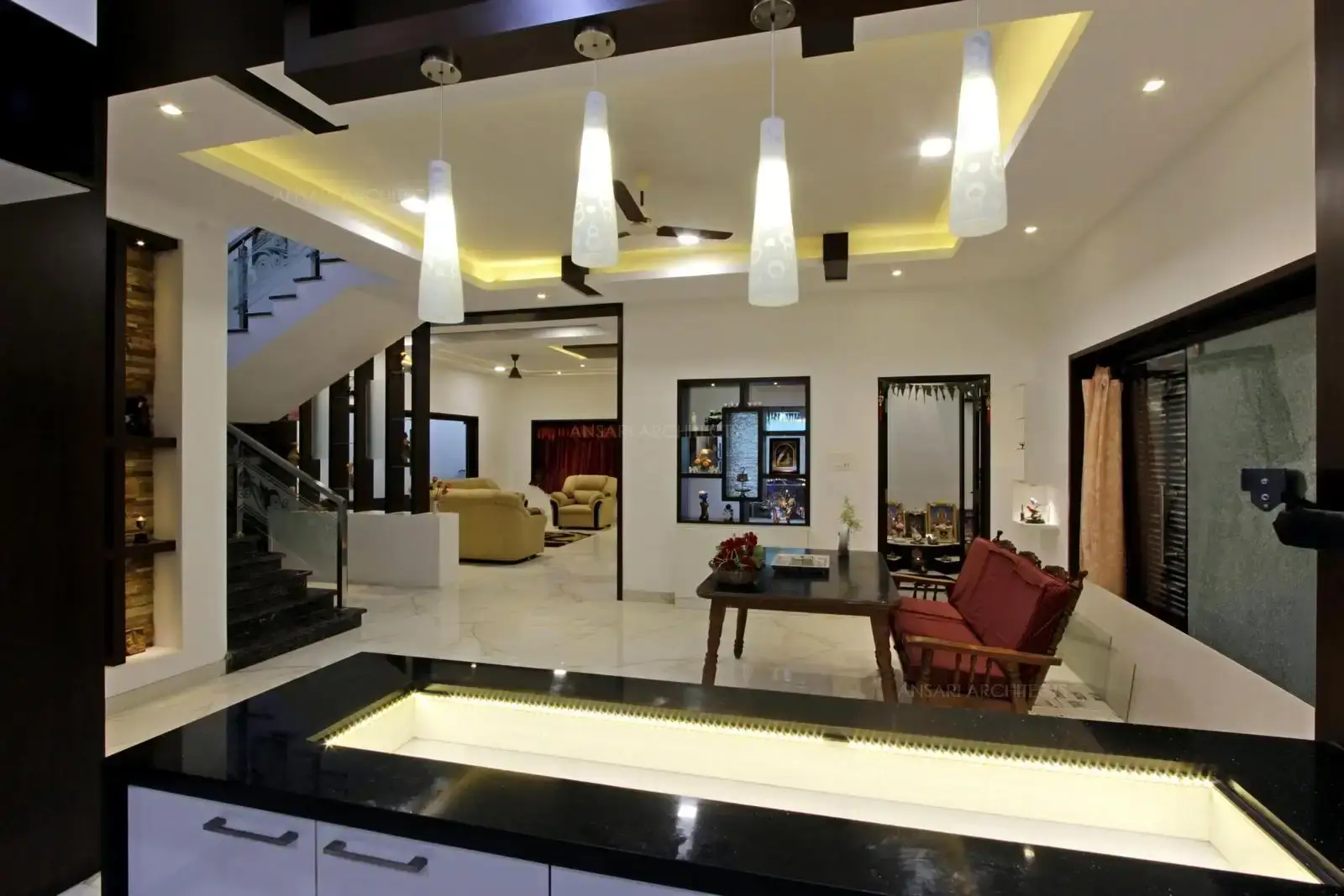Kitchen space gets the right lighting with soft functional tones, over the island area with pendant lights.