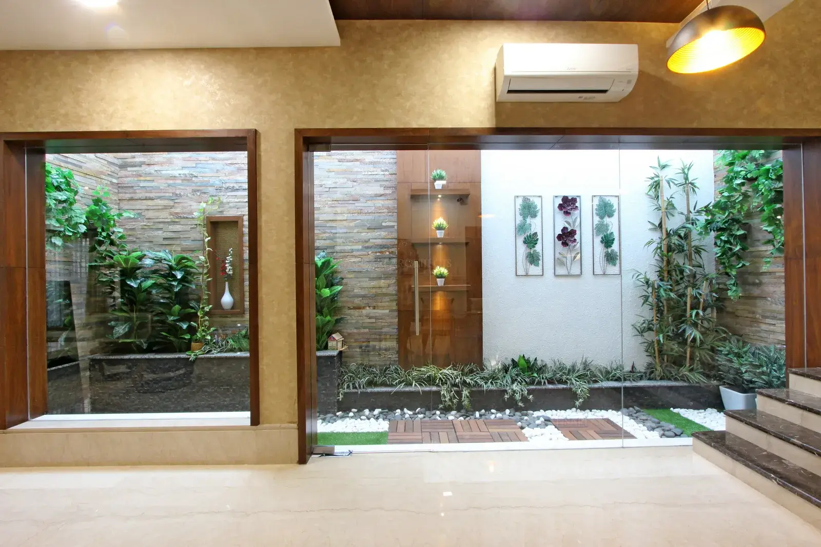 Courtyard is dazzling display in a contemporary room. Intricately designed with varied textures in the space, Wood cladding perfectly inspires with the contrasting stone textures and landscaping with plush-green plants and pebbles offering a serene retreat.