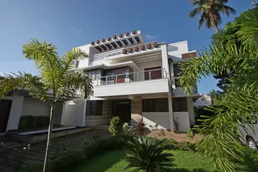 a white house with a lawn and palm trees