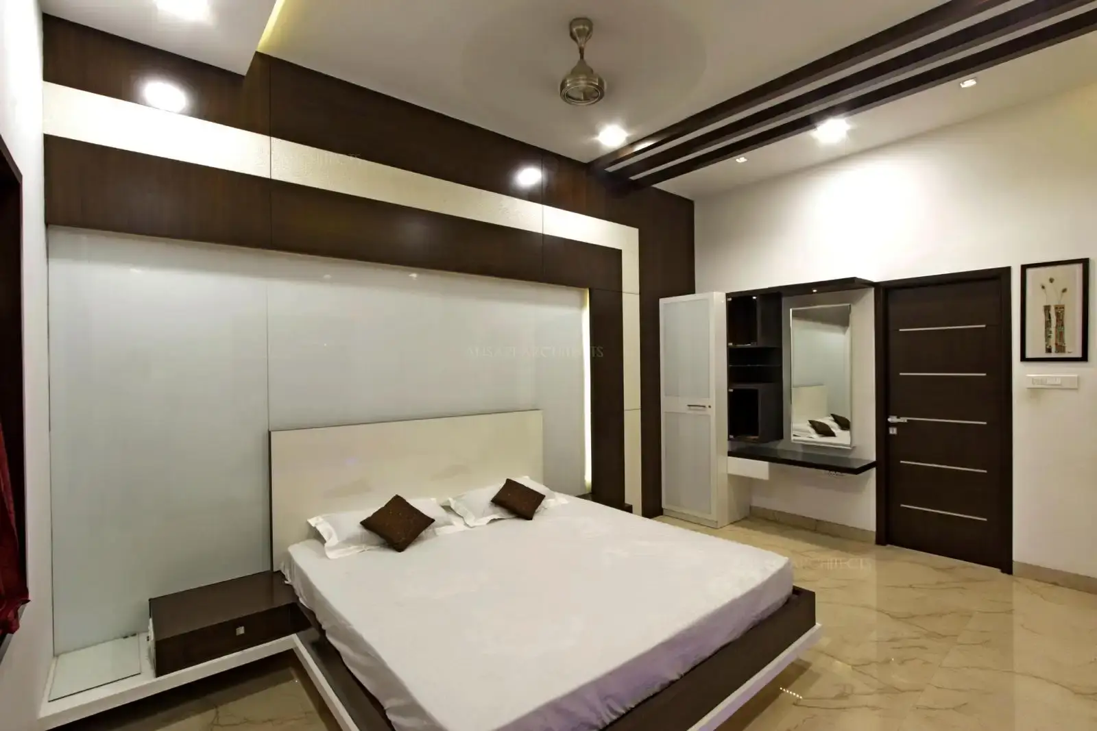 The serene bedroom usues white effectively to bring in a vibe. Marble floor enhances a sense of calmness, the wood elements in the headboard wall offset frame and the ceiling adds layers of warmth.