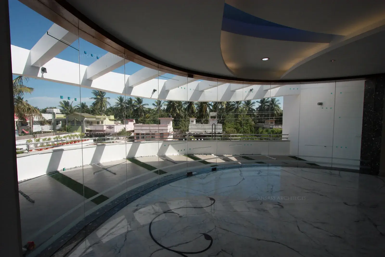 Curved glass wall in the first floor creates an open feel in the family room which overlooks the landscape garden in through the balcony.